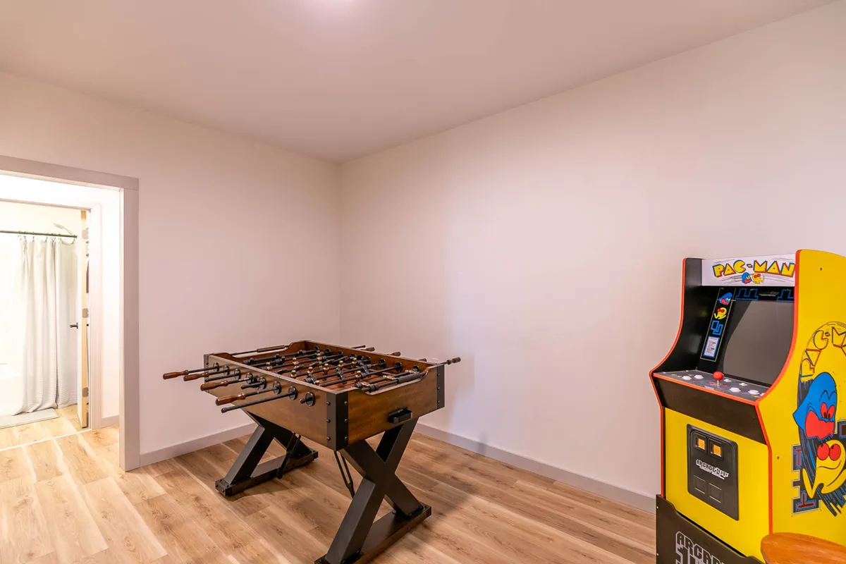 A close-up view of the foosball table and a Pac-Man arcade machine, inviting guests to jump right into a friendly match or nostalgic gaming session. The casual setup suggests a relaxed, fun atmosphere perfect for groups.