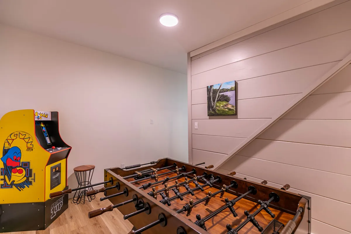 This image features a foosball table and an arcade game machine, set within a lively and inviting interior. The space feels playful and energetic, with painted artwork adding visual interest. The arrangement encourages social interactions and friendly competition.