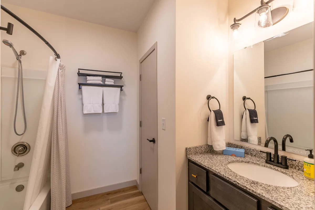 A modern bathroom with a spacious shower area, stylish vanity with sink, and a towel rack, all arranged in an inviting and fresh layout.